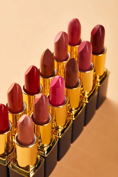 Different red shades of lipstick in tubes on beige — Stock Photo