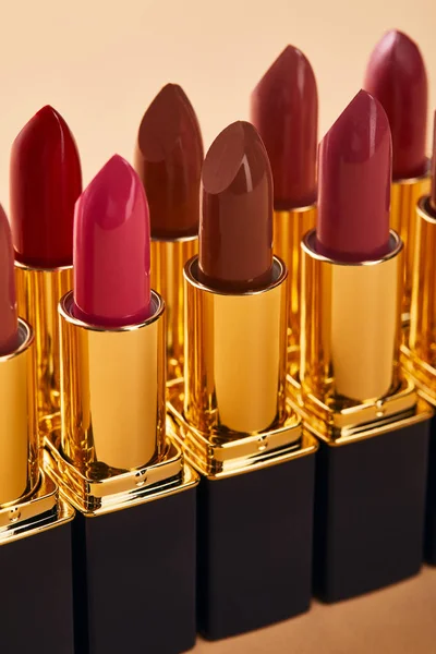 Close up of various red shades of lipstick in tubes isolated on beige — Stock Photo