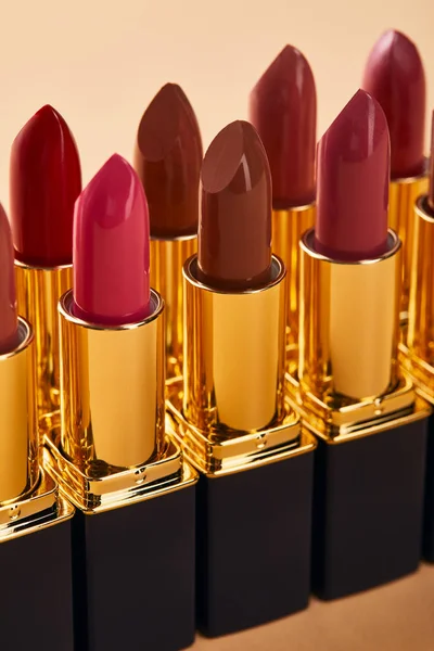 Close up of various red shades of lipstick in tubes isolated on beige — Stock Photo