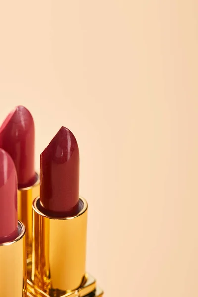 Gros plan de différentes nuances de rouges à lèvres isolés sur beige avec espace de copie — Photo de stock