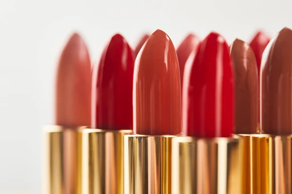 Selective focus of various red shades of lipstick in tubes isolated on grey — Stock Photo