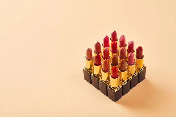 Rouges à lèvres divers sur beige avec espace de copie — Photo de stock