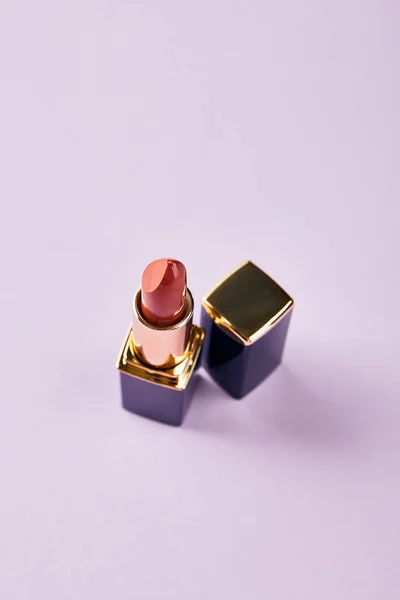 High angle view of single opened tube of red lipstick on purple — Stock Photo