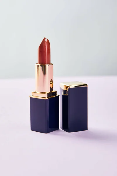 Single opened tube of red lipstick on purple — Stock Photo