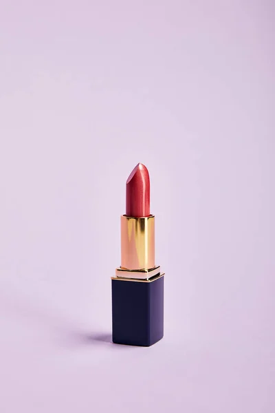Single opened tube of red lipstick on purple — Stock Photo