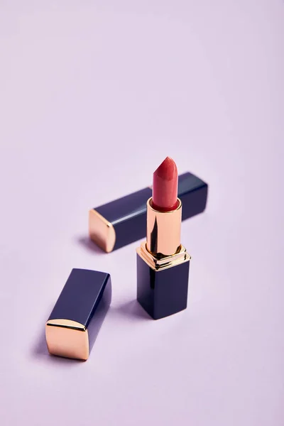 Decorative shiny lipsticks in tubes on violet — Stock Photo