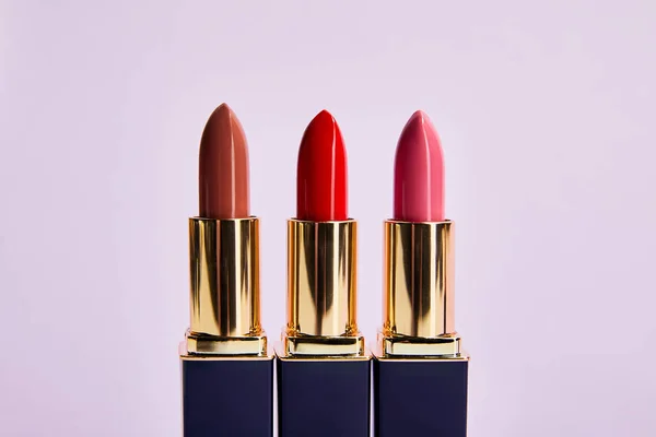 Différentes nuances rouges de rouges à lèvres isolés sur violet — Photo de stock
