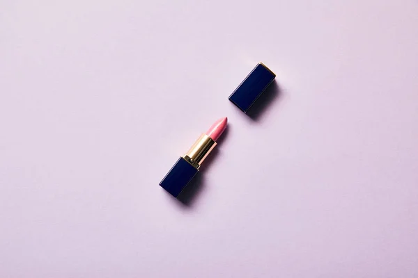 Top view of single opened tube of pink lipstick on purple — Stock Photo