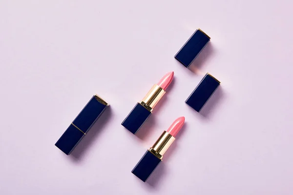 Draufsicht auf verschiedene rosa Schattierungen von Lippenstiften in Röhren auf violett — Stockfoto