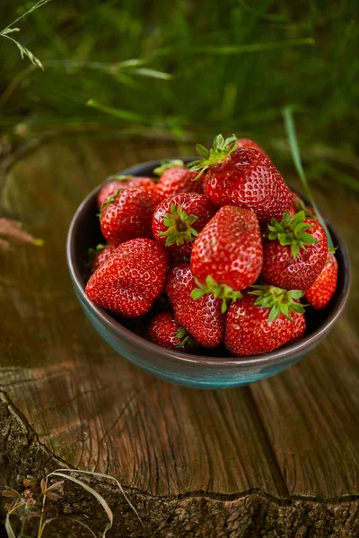 Fresh delicious strawberries in bowl on stump — Stock Photo