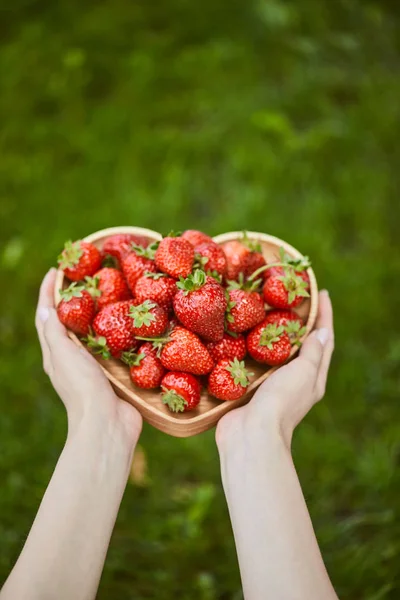 Vue recadrée de la femme tenant la plaque en forme de coeur avec des fraises — Photo de stock