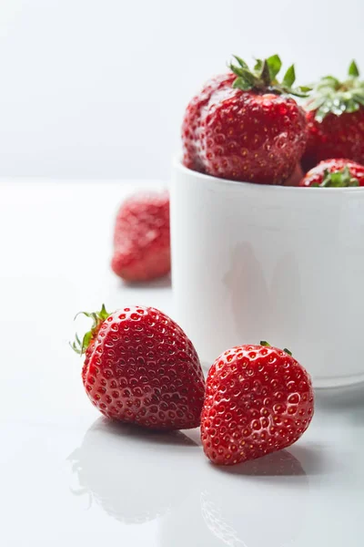 Deliciosos morangos doces vermelhos na xícara no fundo branco — Fotografia de Stock