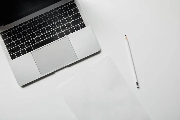 Top view of laptop, paper and pencil on white surface — Stock Photo