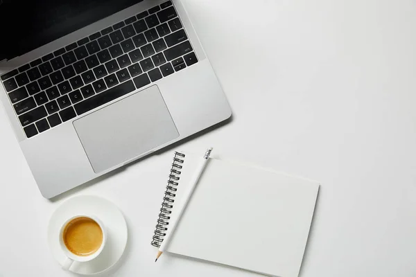 Vista dall'alto di laptop, caffè, notebook e matita sulla superficie bianca — Foto stock