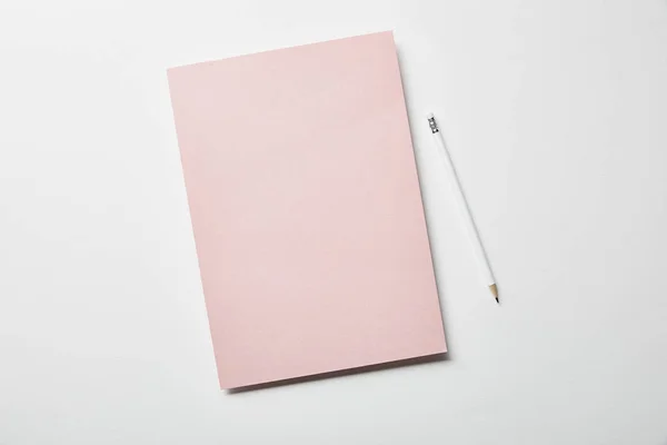 Top view of pink paper and pencil on white surface — Stock Photo