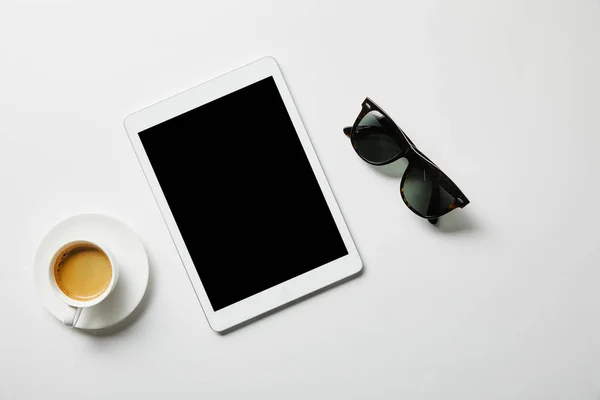 Vista superior do comprimido digital, café e óculos na superfície branca — Fotografia de Stock