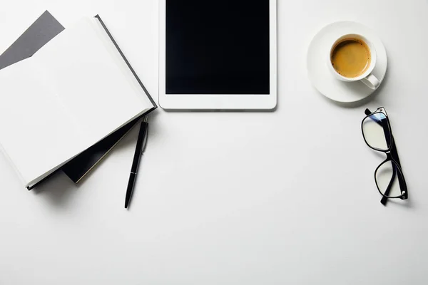 Vue de dessus de tablette numérique, café, lunettes et cahiers avec stylo sur la surface blanche — Photo de stock