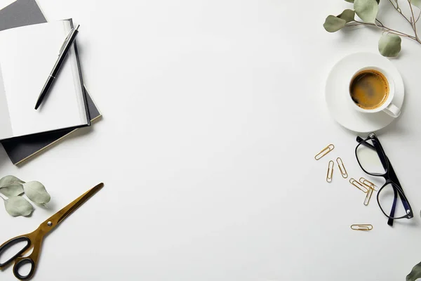 Pflanzen, Schreibwaren, Scheren, Kaffee, Gläser und Notizbücher von oben mit Stift auf weißer Oberfläche — Stockfoto