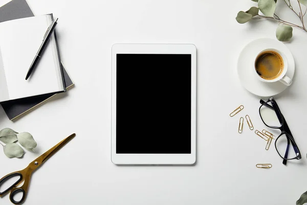 Vue de dessus de tablette numérique, plantes, papeterie, ciseaux, café, lunettes et cahiers avec stylo sur la surface blanche — Photo de stock