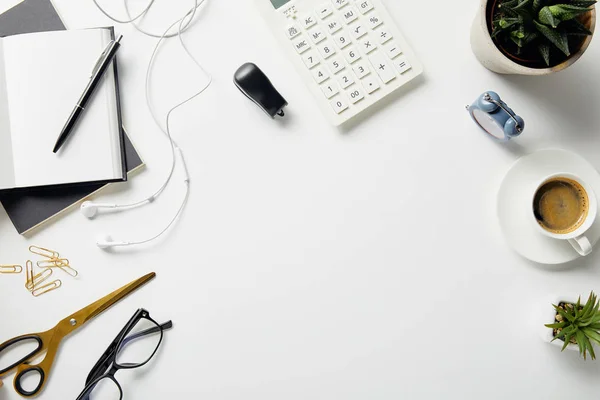 Top view of plants, glasses, coffee, earphones and office supplies on white surface — Stock Photo