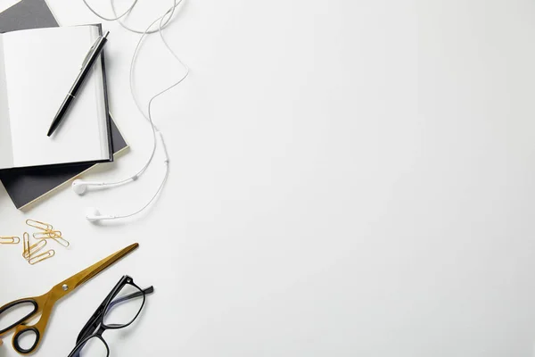 Top view of notebooks, earphones and and office supplies on white surface — Stock Photo