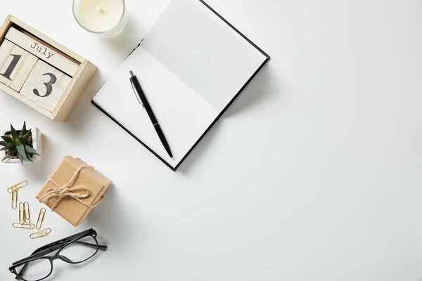 Vue de dessus des blocs avec chiffres et lettres, bloc-notes, stylo, verres, plante et bougie sur la surface blanche — Photo de stock