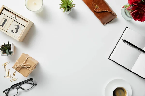 Vue de dessus des blocs avec chiffres et lettres, bloc-notes, stylo, étui, verres, plantes et bougie sur la surface blanche — Photo de stock