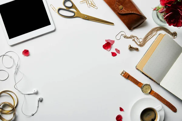 Vue du dessus de tablette numérique, bloc-notes, étui, écouteurs, plantes, fournitures de bureau et café avec des bijoux sur la surface blanche — Photo de stock