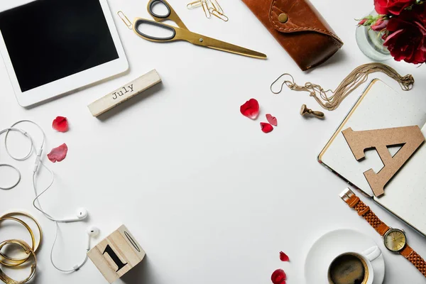 Draufsicht auf digitales Tablet, Kopfhörer, Schmuck, Tasche, Blumen, Bürobedarf und Kaffee auf weißer Oberfläche — Stockfoto