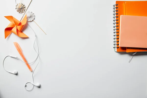 Vista superior de cuadernos naranja, objetos de decoración y auriculares en la superficie blanca - foto de stock