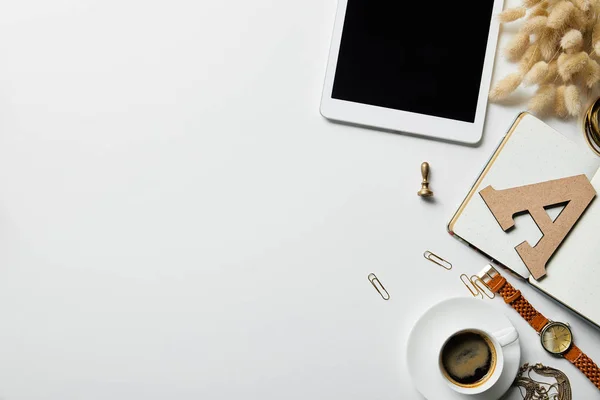 Vista dall'alto di tablet digitale, cancelleria, caffè, orologio e notebook su superficie bianca — Foto stock