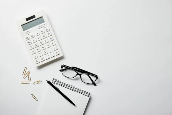 Vista superior de artigos de papelaria, calculadora e notebook com caneta na superfície branca — Fotografia de Stock