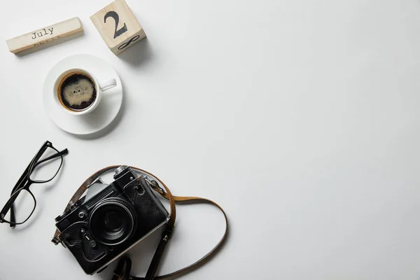 Vista superior de la cámara de fotos, vasos, café, bloque con números y letras en la superficie blanca — Stock Photo