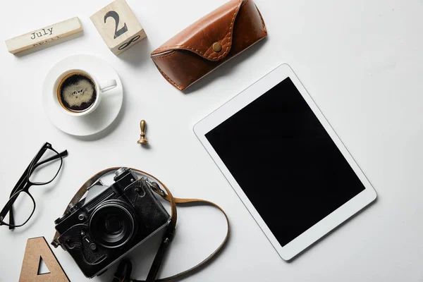 Top view of digital tablet, photo camera, coffee, case, block with numbers and letters on white surface — Stock Photo