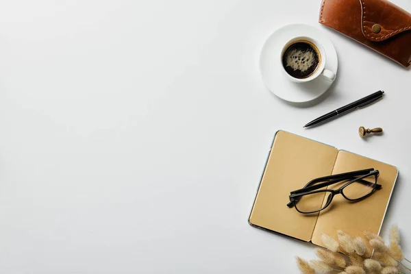 Vista superior do café, bloco de notas com caneta e caixa na superfície branca — Fotografia de Stock