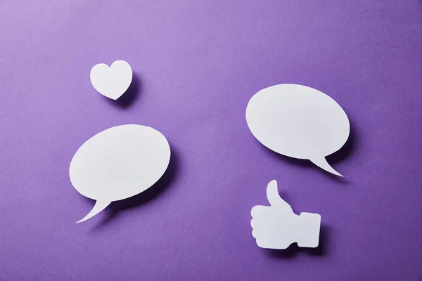 White speech bubbles, thumbs up card and small paper heart on purple surface — Stock Photo
