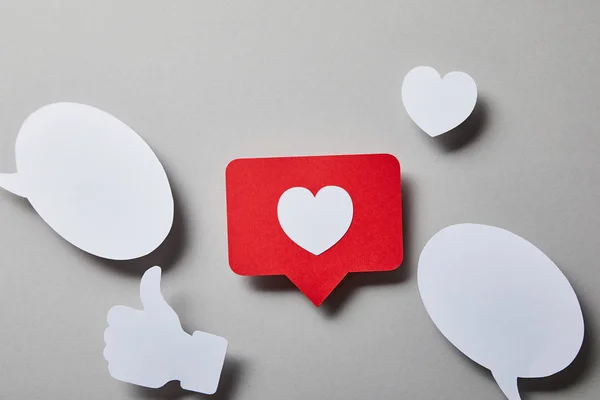 Red like card, speech bubbles, thumbs up and small paper heart on white surface — Stock Photo