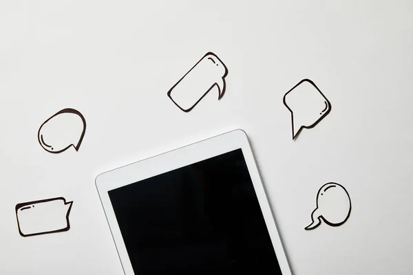 Digital tablet with paper thought and speech bubbles on white surface — Stock Photo