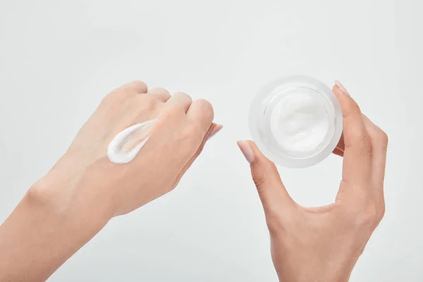 Cropped view of woman with cream in hand and skin isolated on white — Stock Photo