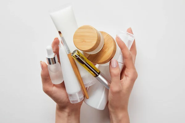 Cropped view of woman hands with cosmetics in tubes, dispensers, bottles and jar isolated on white — Stock Photo