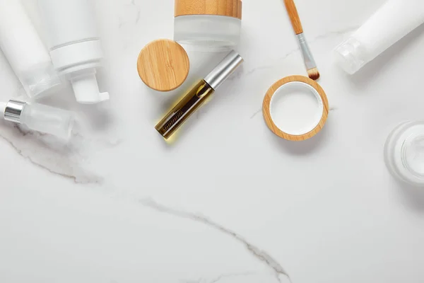 Ausgeschnittene Ansicht von Cremetuben, Kosmetikdosen, Spender und Glasflasche mit Augenbürste auf weißer Oberfläche — Stockfoto