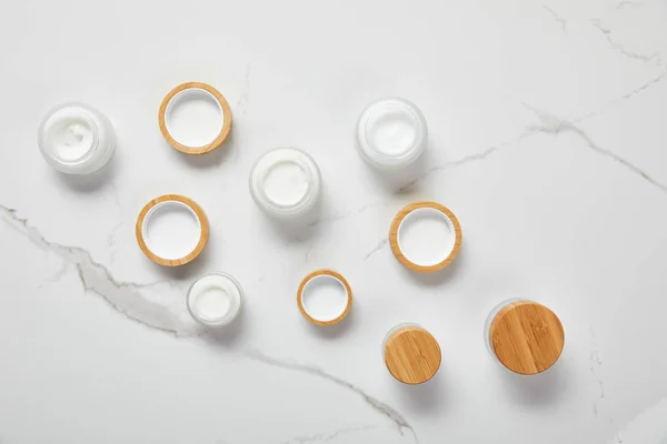 Vue de dessus des bocaux avec crème cosmétique sur la surface blanche — Photo de stock