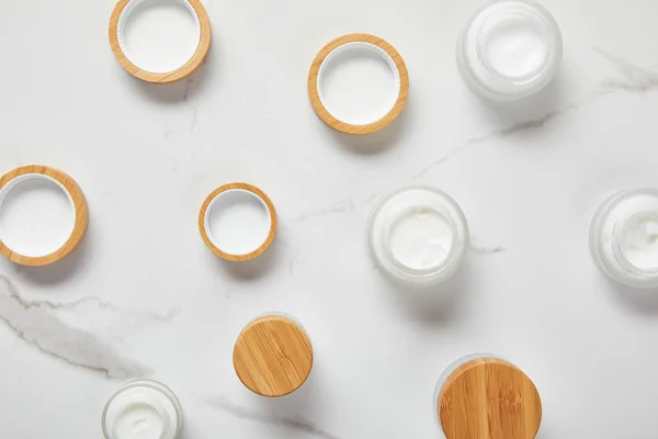 Vue de dessus des bocaux avec crème cosmétique sur la surface blanche — Photo de stock