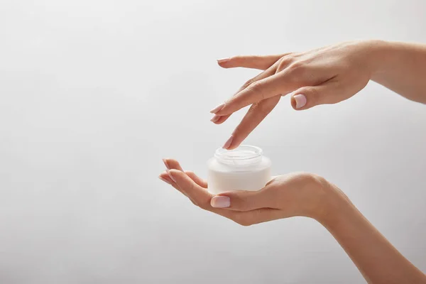 Vista ritagliata delle mani della donna che tengono il vaso con crema isolata su bianco — Foto stock