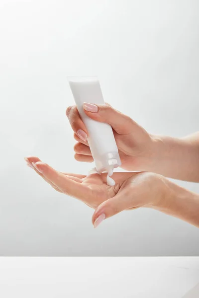 Vue recadrée de la femme tenant tube cosmétique dans les mains, l'application de crème sur la peau — Photo de stock