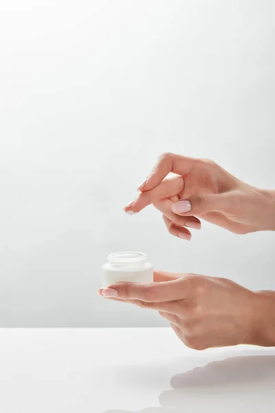 Cropped view of woman holding jar with cream in hands — Stock Photo