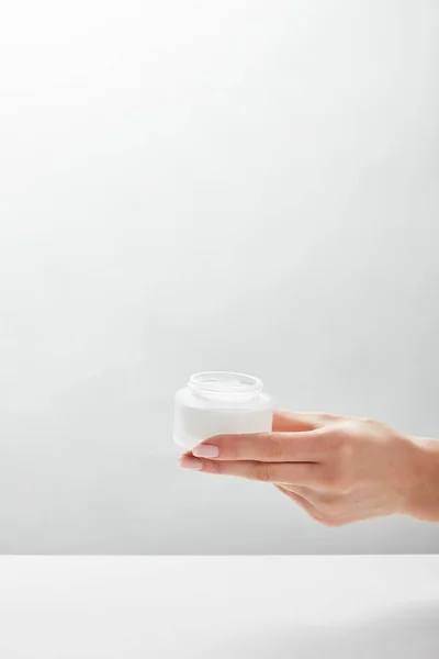 Cropped view of woman holding jar with cream in hand — Stock Photo