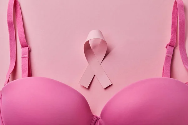 Вид зверху бюстгальтера біля стрічки на рожевому фоні, концепція раку молочної залози — стокове фото