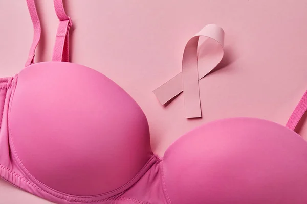 Ruban près du soutien-gorge sur fond rose clair, concept de cancer du sein — Photo de stock