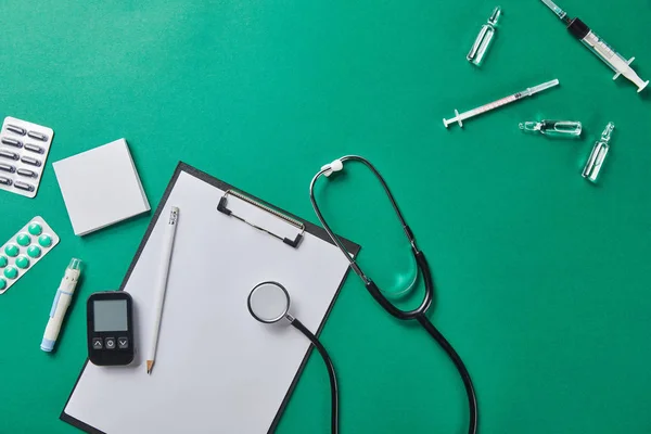 Top view of various medical supplies near folder and stethoscope on green surface — Stock Photo